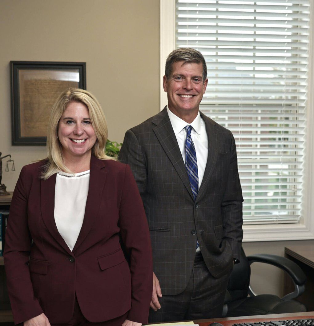 Dzenitis Newman Two Dzenitis Newman attorneys standing together in a firm office