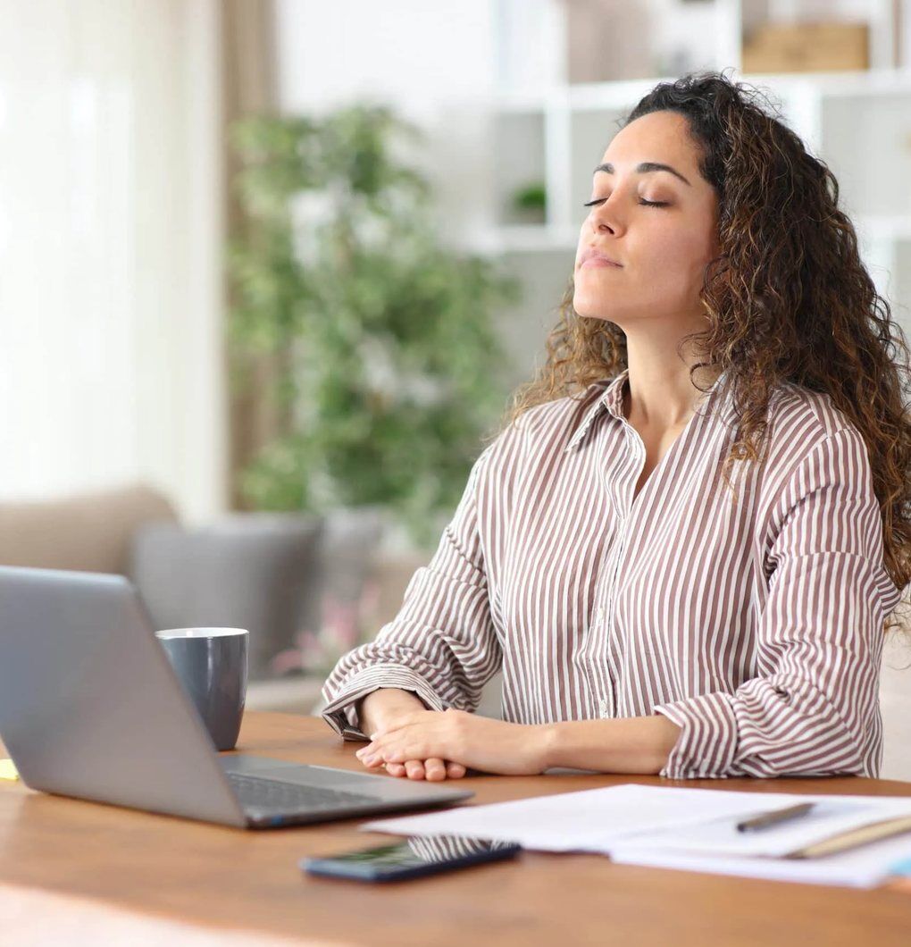 Roaring Brook Recovery A woman pausing with her eyes closed at a desk, from the Roaring Brook Recovery website